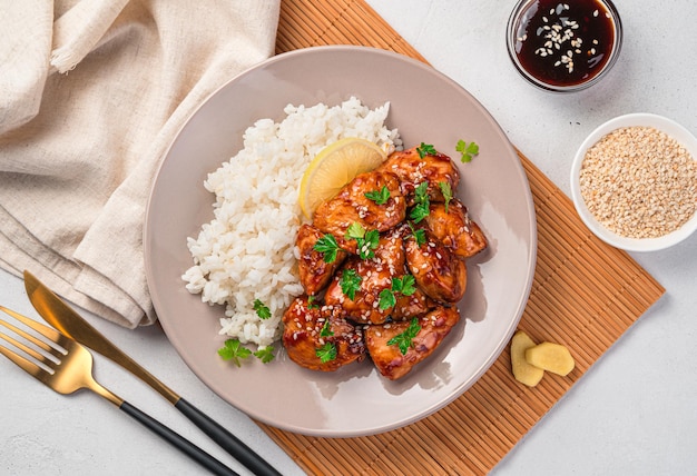 Pollo teriyaki con semillas de sésamo, arroz y perejil fresco sobre un fondo claro. Vista superior.