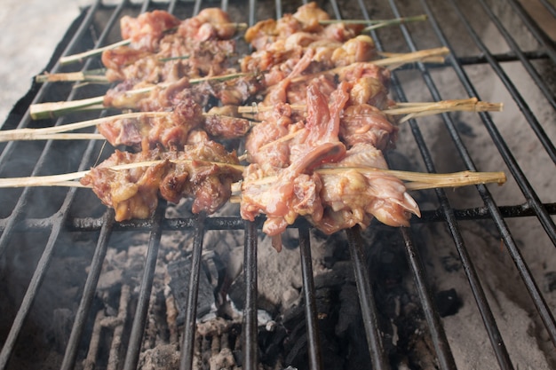 Pollos a la parrilla en la estufa de hierro, chimenea, comida de la calle de Tailandia.