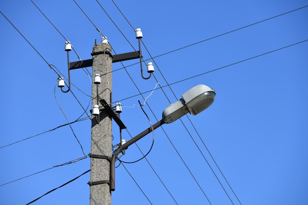 Pólo elétrico concreto velho para a transmissão de eletricidade com fio com poste de luz em um fundo de um céu azul nublado. Me obsoleta. Thod de fornecer eletricidade