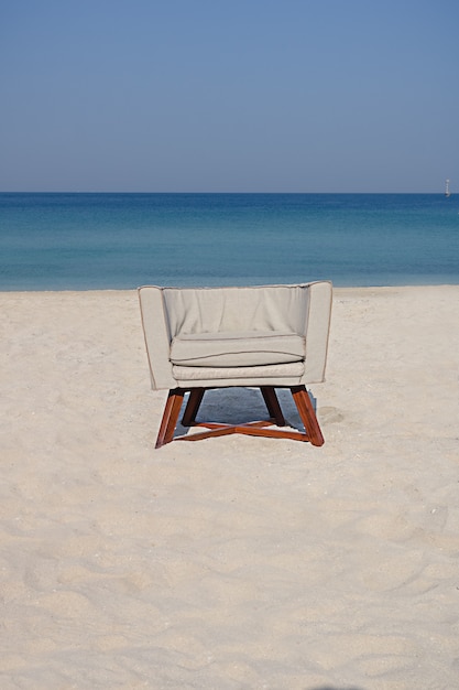 Foto poltrona vazia de pé na areia à beira-mar