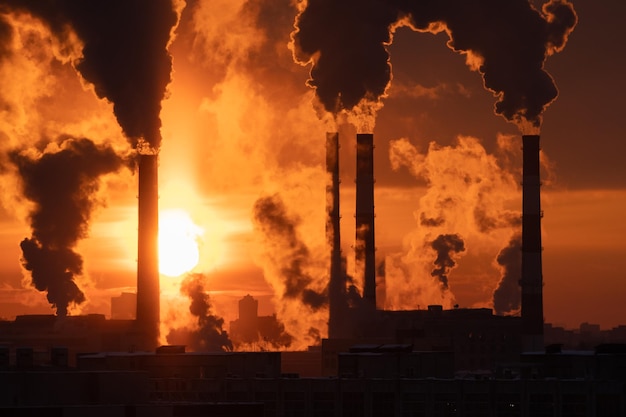 Poluição do ar e chaminés de fumaça de aquecimento global da usina térmica ao pôr do sol na cidade de inverno