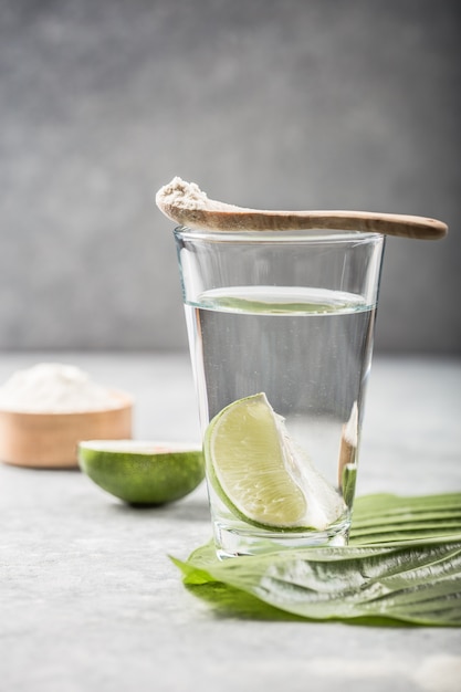 Polvo de colágeno y vaso de agua con rodaja de limón