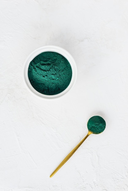 Polvo de espirulina en una cuchara y un bol