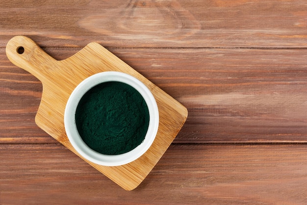 Polvo de espirulina en un recipiente sobre una tabla de madera Espacio de copia de vista superior de orientación horizontal