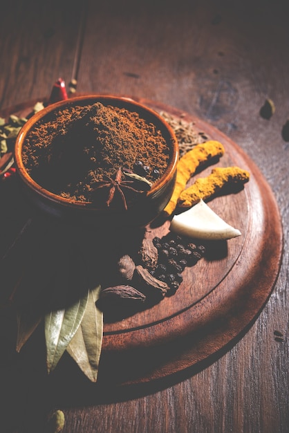 Polvo indio de Garam masala en un tazón y sus ingredientes especias coloridas. Servido sobre fondo de mal humor. enfoque selectivo