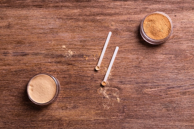 Polvo mineral de diferentes colores con un dispensador de cuchara para maquillaje sobre fondo de madera