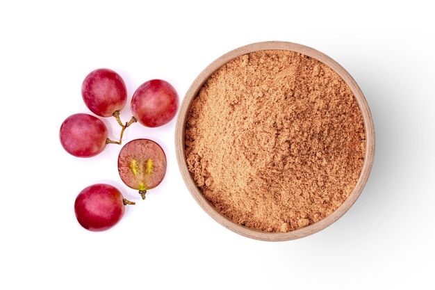 Foto polvo de semilla de uva en tazón de madera y uvas rojas frescas aisladas sobre fondo blanco vista superior