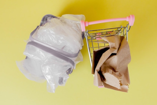 Polythen und Papiertüten in einem Einkaufskorb auf einem gelben Hintergrund