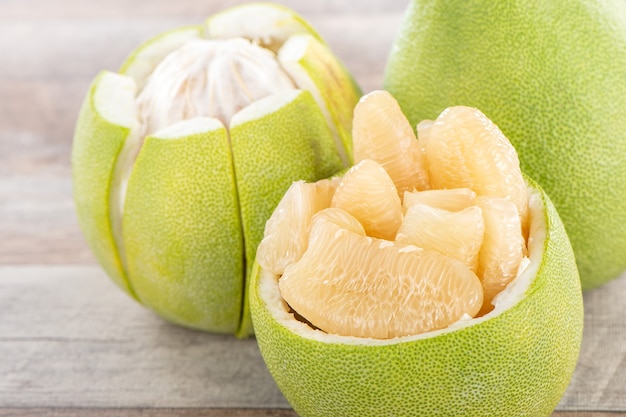 Pomelo fresco y pelado (shaddock), pomelo con rodajas sobre fondo de mesa de madera