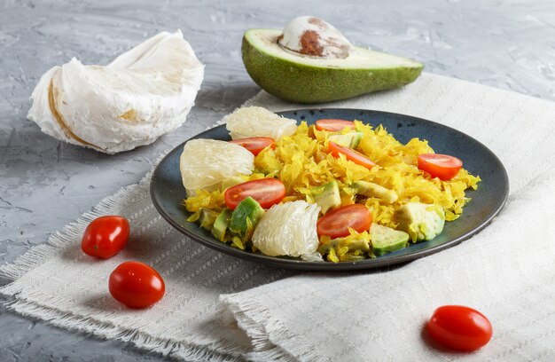 Pomelo frito con tomate y aguacate sobre fondo gris de concreto