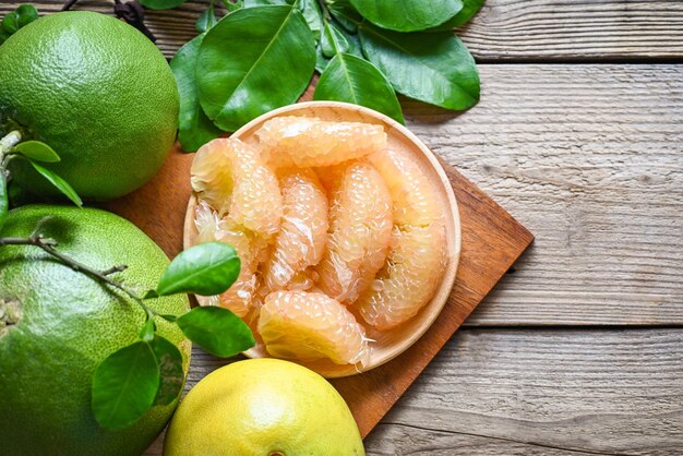 Foto pomelo fruta em placa de madeira fundo pomelo verde fresco descascado e folha de pomelo árvore pomelo toranja no verão fruta tropical na tailândia