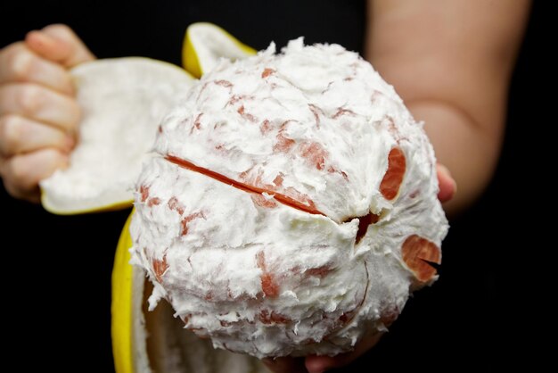 Foto pomelo fruto cítrico con carne roja dulce y cáscara gruesa amarilla en negro