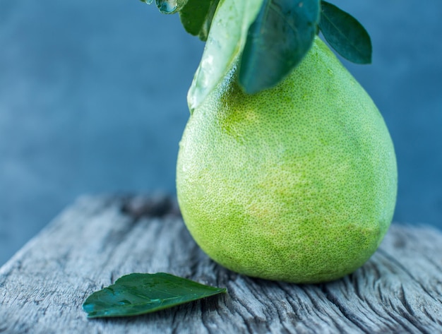 Pomelo con hojas verdes sobre una tabla de madera