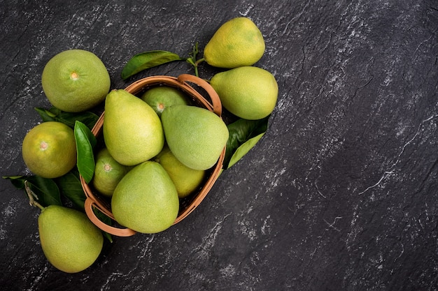 Pomelo pelado fresco, pomelo, pomelo, shaddock sobre fondo oscuro en la canasta de bambú. Fruta de temporada de otoño, vista superior, plano, plano de mesa.