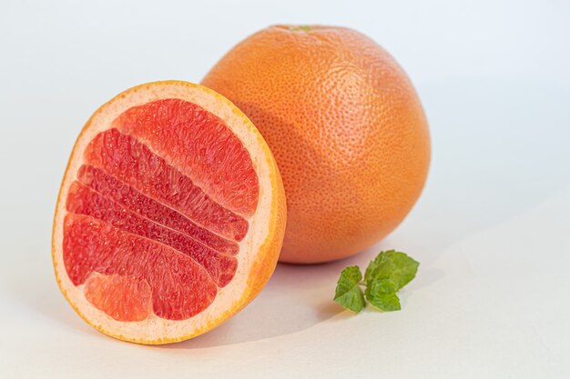 Pomelo en un plato blanco con una ramita de menta. Aislar. Copie el espacio.