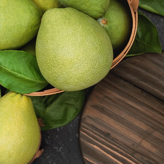 Pomelo pomelo fresco en cesta de bambú con hoja verde sobre fondo de pizarra negra oscura Fruta de temporada para el Festival de Medio Otoño Vista superior Lay Flat