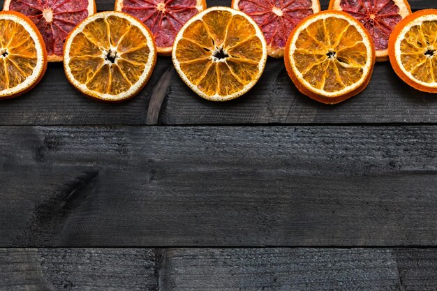 Pomelo seco y rodajas de naranja sobre una mesa de madera oscura