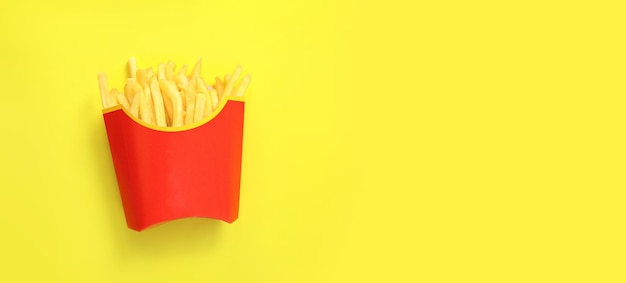 Foto pommes frites auf gelbem hintergrund, draufsicht. kartoffeln in papierverpackung