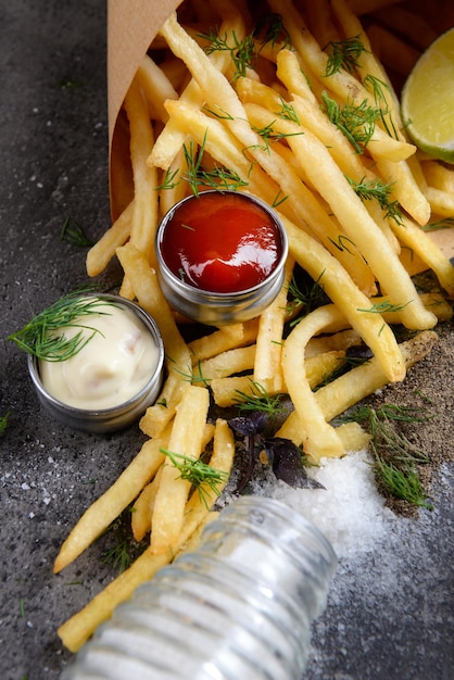 Pommes frites im Beutel mit Sauce Limette und Gewürzen auf dem Tisch