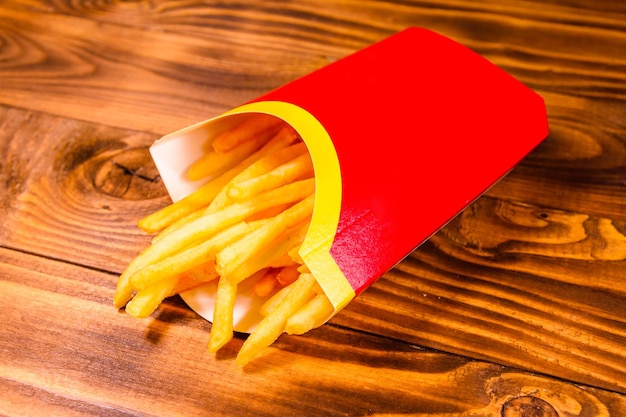 Pommes frites im roten Kasten auf Holztisch