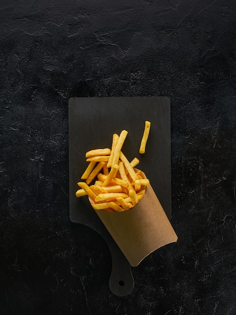 Pommes Frites in einer Bastelpapierbox auf Holzbrett, Draufsicht mit Kopierraum