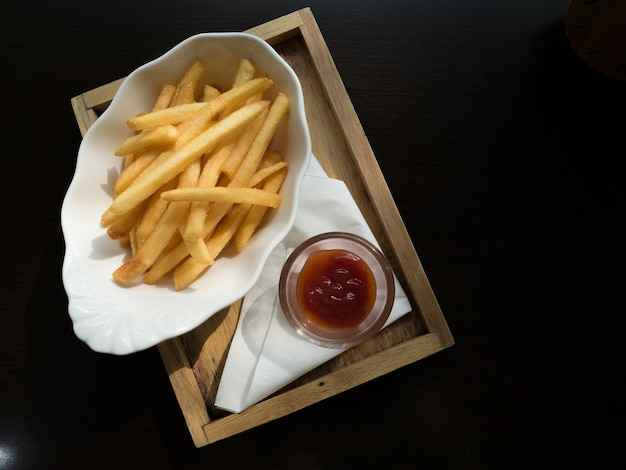 Pommes-Frites in einer Schüssel auf einem hölzernen Hintergrund