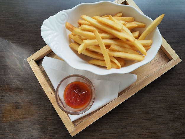 Pommes-Frites in einer Schüssel auf einem hölzernen Hintergrund