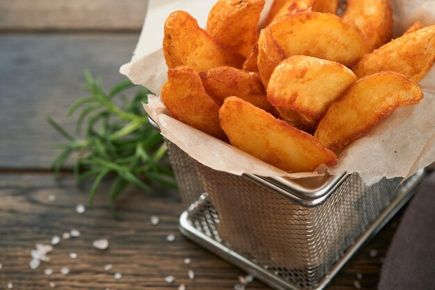 Pommes Frites in Metalldrahtkorb mit Salz und Ketchup auf altem dunklem Holzhintergrund clous up Bratkartoffeln Fast Food und ungesundes Lebensmittelkonzept