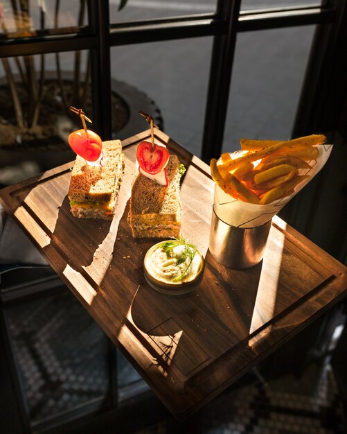 Pommes Frites mit Sandwiches auf einem Holzteller