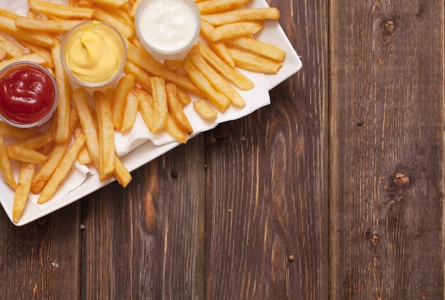 Pommes frites mit Sauce auf Holztisch.