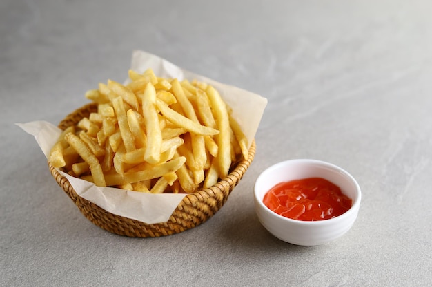 Pommes Frites mit Soße auf einem Holzteller isoliert mit grauem Hintergrund