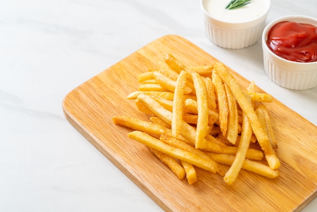 Pommes Frites oder Kartoffelchips mit Sauerrahm und Ketchup