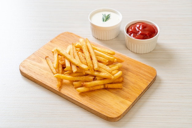 Pommes Frites oder Kartoffelchips mit Sauerrahm und Ketchup