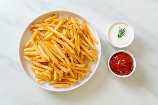 Pommes Frites oder Kartoffelchips mit Sauerrahm und Ketchup