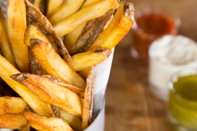 Foto pommes frites sind kartoffeln, die hergestellt werden, indem sie in stäbchen geschnitten und in heißem öl gebraten werden