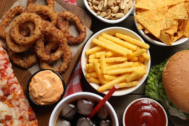 Pommes-Frites-Zwiebelringe und anderes Fast Food auf Holztisch flach liegen