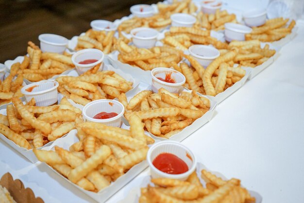 Pommes im Pappteller in der Reihe werden servierfertig auf dem Tisch angeordnet