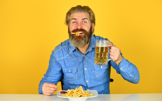 Pommes-Kartoffel-Typ in der amerikanischen Bar, der Bierglas trinkt und Kartoffeln isst