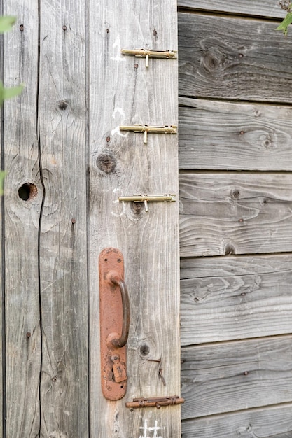 Pomo oxidado y tres pestillos en un granero de madera o puerta de baño en el campo