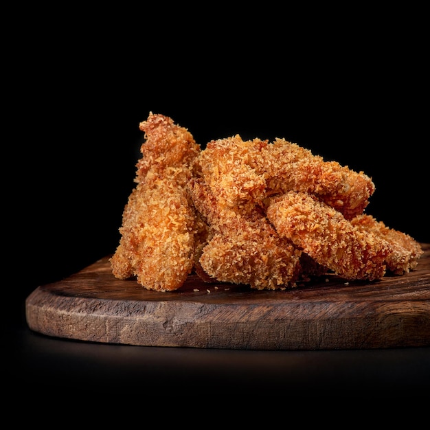 Pon las patas de pollo fritas en una bandeja de madera aislada en negro
