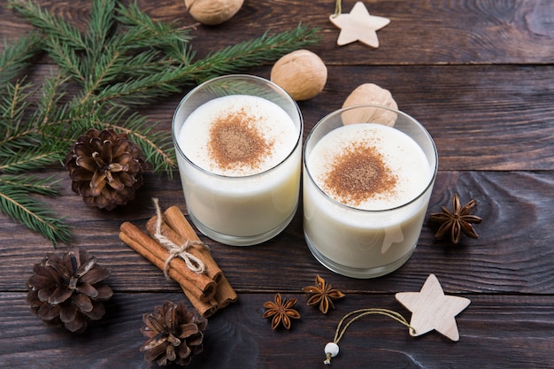 Ponche de huevo con canela en copas, decoración navideña, bebida festiva tradicional.