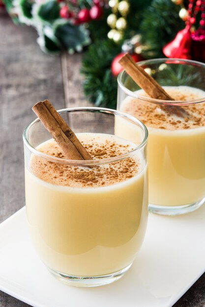 Ponche de huevo casero con canela en mesa de madera Postre típico de Navidad.