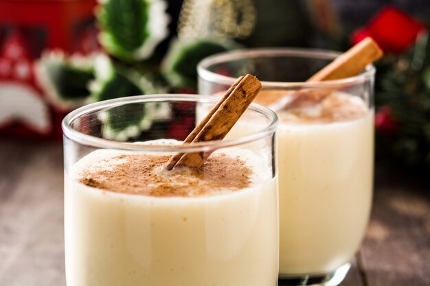 Ponche de huevo casero con canela en vidrio sobre mesa de madera, postre típico de Navidad