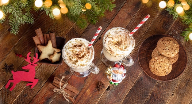 Ponche de huevo de Navidad, decoraciones de galletas de canela, ramitas de abeto, luces de Navidad en la mesa de madera, vista superior