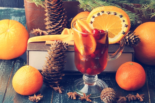 Ponche quente com laranja cranberry e especiarias. Cones de abeto vintage de Natal com fundo de madeira antigo estilo rústico