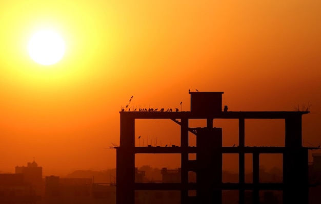 Foto pondo o sol atrás de um prédio de construção em bangladesh