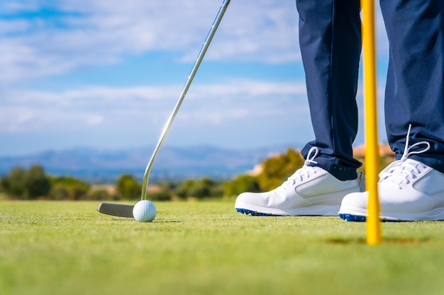 Poner la bola en el hoyo en el green con el hombre del putter jugando al golf