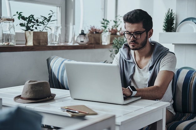 Foto poner ideas en algo real. apuesto joven moderno en gafas con computadora