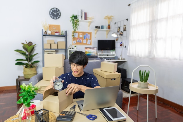 Poner en marcha pequeñas empresas hombre asiático joven empresario preparando paquetes de cajas de cartón de embalaje