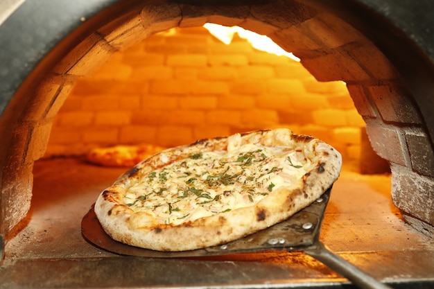 Foto poner pizza en el horno de leña